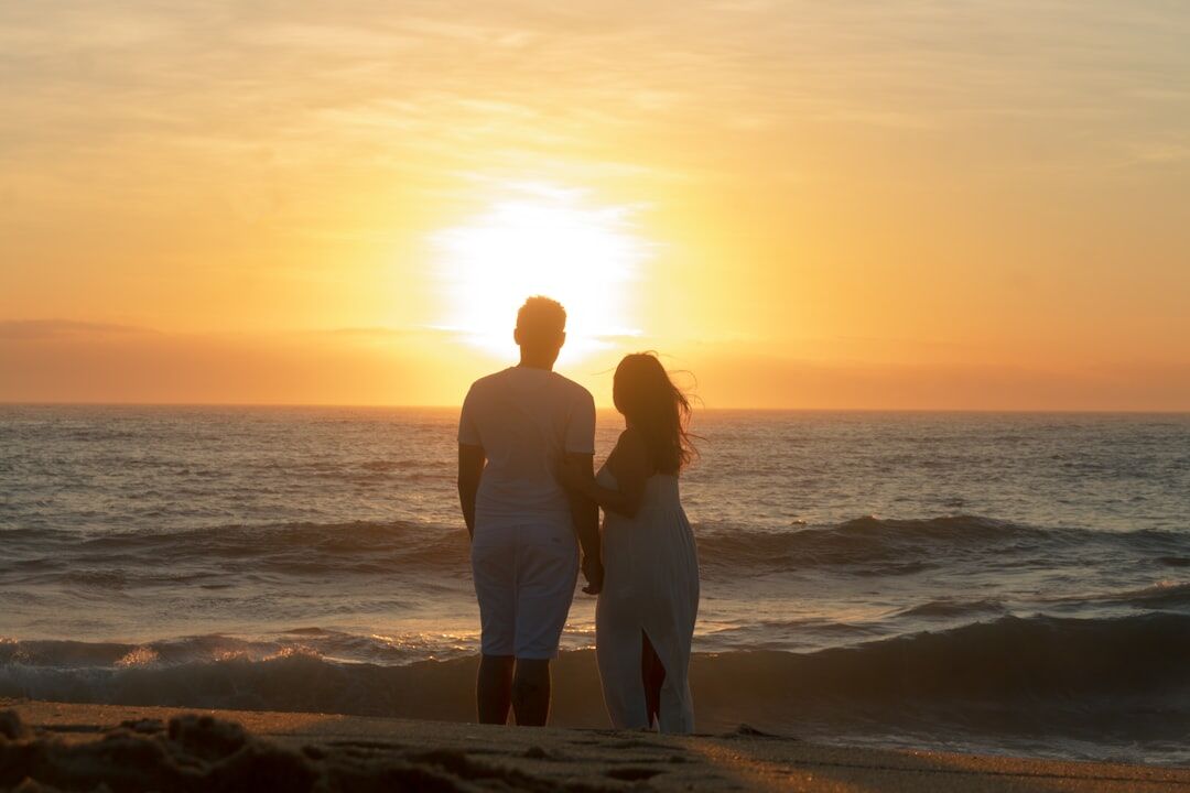romantic couple walking beach at sunset